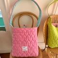 Detalle de bolso acolchado rosa con forro azul y parche de logo sobre una silla de madera - Estilo Reversible Acolchado Corazón Rosa Baya