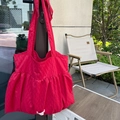 Detail of red pleated tote bag with perforated texture and white logo tag outdoors - Red Polka Dot