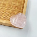 Pierre de quartz rose naturel poli en forme de cœur sur un plateau en bambou - Quartz rose