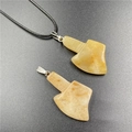 Pale yellow natural stone axe pendant necklace with a black cord on a dark background - Topaz