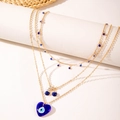 Collier multicouche doré avec pendentifs cœur bleu, œil grec et cerise sur support blanc - Or + Mauvais Œil Cerise Pierre Bleue (28716-gold)