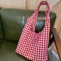 Classic red and white gingham cotton tote bag displayed on a dark green leather sofa - Red Plaid