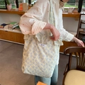 Light blue floral canvas tote bag with ruffled trim and Bisket label carried by model - Blue Floral Ruffle Shoulder Bag