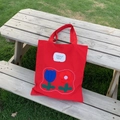 Borsa tote in nylon rosso con ricamo floreale e testo motivazionale su panca - Rosso