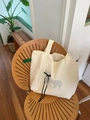 Detail of cream tote bag featuring butterfly bow and green label on wood background - Double Layer Beige Puppy