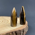 Polished tiger eye crystal bullet stones displayed on a natural wood slice base - Tiger's Eye