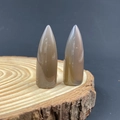 Brown translucent agate bullet-shaped stones displayed on a natural wood ring stand - Grey Agate
