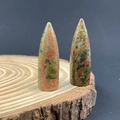 Polished Unakite stone bullet points with natural green and pink patterns on wood base - Unakite