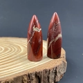 Polished Red Jasper bullet-shaped energy stones displayed on a natural wood base - Red Jasper