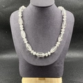 Détail d'un collier en cristal blanc naturel avec des perles à facettes sur un buste - Cristal blanc