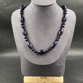 Détail du collier en pierre de sable bleu avec perles ovales et rondes sur support gris - Pierre de Sable Bleu (Synthétique)