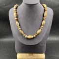 Détail d'un collier en pierres naturelles colorées sur un buste d'exposition gris - Unakite