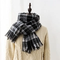 Classic black and grey plaid cashmere-style scarf with fringe on a cable knit sweater - Black