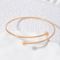 Minimalist open gold bangle with polished metal spheres on a clean white display stand - Minimalist Double Round Ball Open Style (24784-gold)