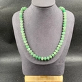 Green natural stone necklace with translucent round beads on a grey jewelry display - Green Aventurine