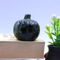 Green natural stone pumpkin figurine with black textures on a beige book - Sparrow Stone