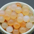 Polierte 8mm porenfreie natürliche orangefarbene Aventurin-Steine in einer weißen Schale - Natürlicher Roter Achat