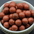 Deep reddish-brown goldstone round beads with sparkling gold flecks in a ceramic bowl - Gold Sand Stone (Synthetic)