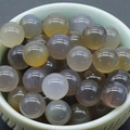 Polished 8mm natural green aventurine round beads in a light cyan ceramic bowl - Grey Agate