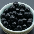 Polished 8mm black stone beads without holes displayed in a textured ceramic bowl - Obsidian