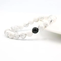 Pulsera de turquesa blanca con una cuenta de ágata negra sobre un soporte de cerámica - Turquesa Blanca Natural