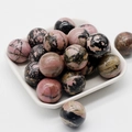 Polished 20mm rhodonite stone sphere with pink base and black natural textures - Rhodonite