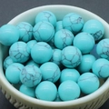 Green aventurine natural stone beads with black mesh texture in white porcelain bowl - Synthetic Turquoise