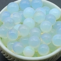 8mm translucent opalite glass beads with soft blue glow displayed in a white bowl - Opal (Synthetic)