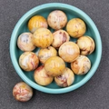 Polished 20mm natural crazy lace agate stone spheres in a green ceramic bowl - Crazy Agate