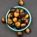 Polished natural tiger eye crystal spheres with golden-brown bands in a ceramic bowl - Tiger's Eye
