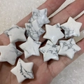 Piedras de howlita blanca pulidas en forma de estrella sostenidas para ver el tamaño - Howlita