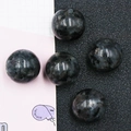Polished dark grey labradorite crystal spheres with natural flecked texture on dark surface - Larvikite