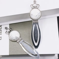 Two vintage antique silver crown bookmarks with white marble stones on white book - Howlite