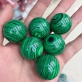 Sfere di malachite lucida da 30mm con texture a strisce verdi tenute in mano - Malachite (Sintetico)