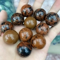 Polished 25mm mahogany obsidian and brown natural stone balls held in hand - Mahogany Obsidian