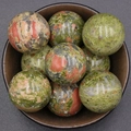 Polished unakite stone spheres with green and orange patterns in a ceramic bowl - Unakite