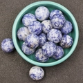 Spherical 20mm blue sodalite stone beads with natural marble texture on a ceramic plate - Blue Spot Jasper