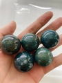 Set of five polished green moss agate 30mm natural stone spheres held in hand - India Agate