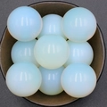 Nine translucent opal spheres with blue glow arranged in a rustic dark wooden bowl - Opal (Synthetic)