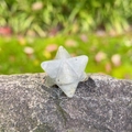 Handgefertigter Labradorit Merkaba Stern Kristallstein auf einer grauen Felswand - Labradorit
