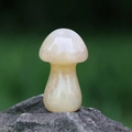 Polierter gelber Naturkristallstein in Pilzform auf grauem Felsenhintergrund - Roter Aventurin