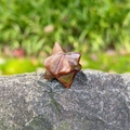 Polished tiger eye stone Merkaba star crystal with natural striped texture on gray rock - Red Tiger Eye