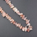 Irregular natural pink-orange raw stone beads on a red cord for DIY jewelry making - Strawberry Quartz