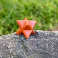 Polished red jasper Merkaba star crystal stone ornament on natural rock background - Red Jasper