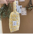 Close-up of quilted cotton handbag with yellow and purple checkered pattern and floral label - Yellow Plaid Makeup Bag