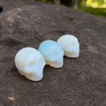 Tre teschi intagliati in cristallo di opalite su roccia naturale per Halloween - Opale Sintetico