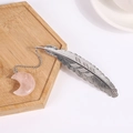 Silver feather metal bookmark with pink crystal moon pendant on a wooden tray - Rose Quartz