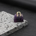 Miniature amethyst handbag pendant with gold handle on textured volcanic stone - Amethyst