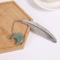 Silver feather bookmark with a green crystal crescent moon pendant on wooden tray - Green Aventurine