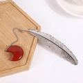 Silver feather metal bookmark with red agate moon pendant on a wooden tray - Rainbow Stone
